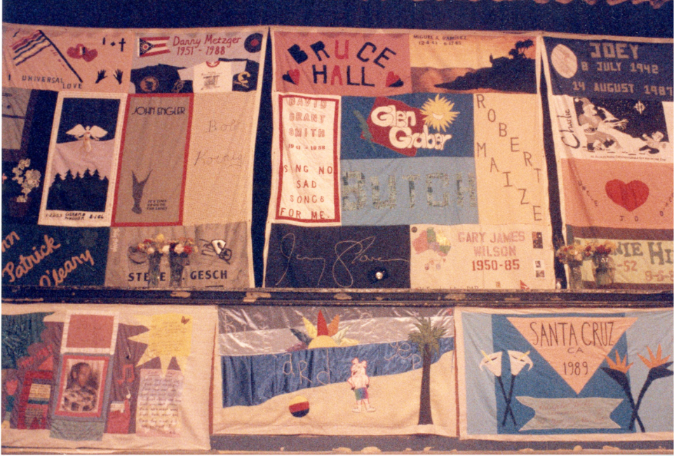 AIDS quilt sections hang from ceiling.